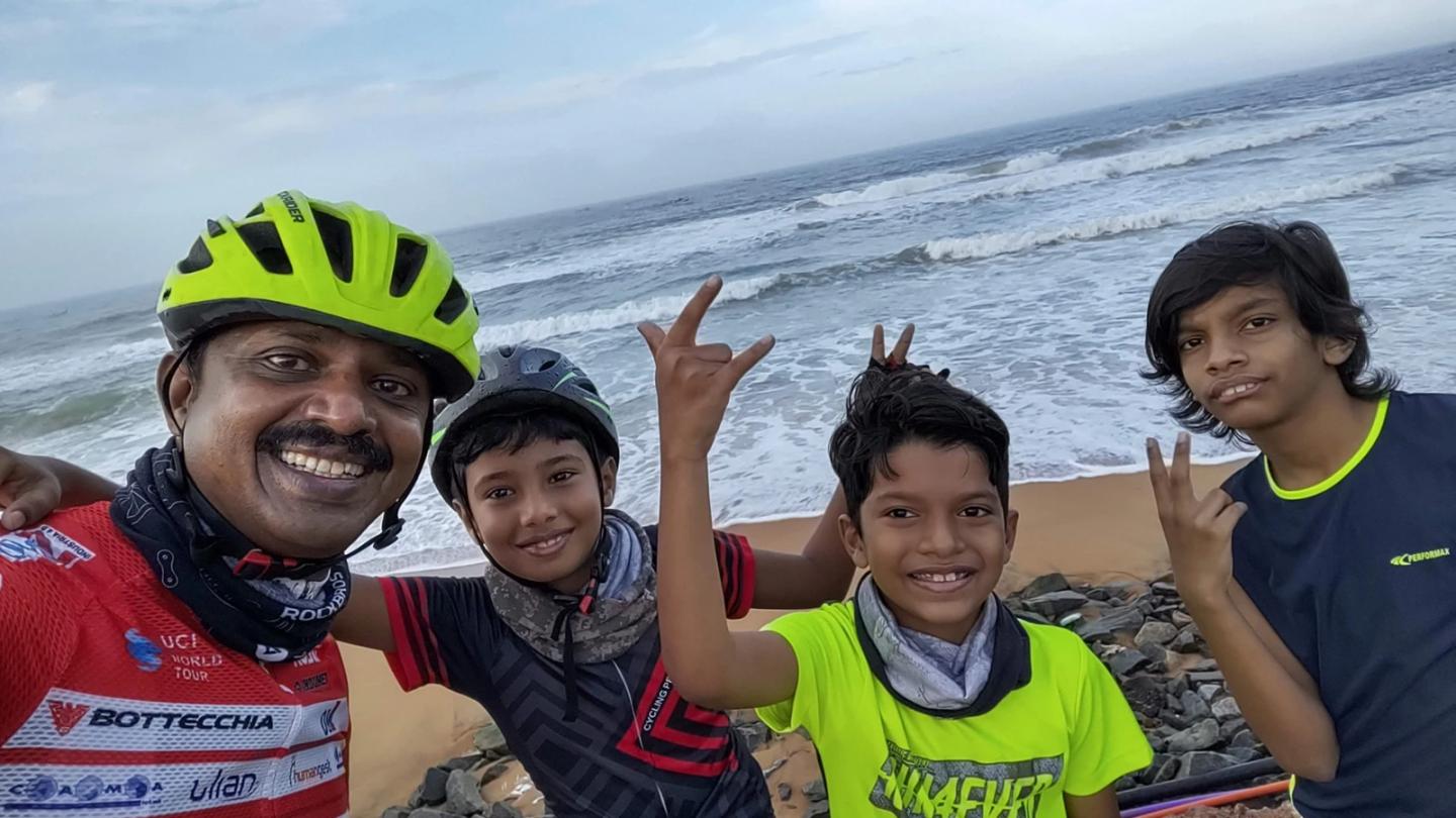 Children and an adult posing beside the sea during a recreational ride.