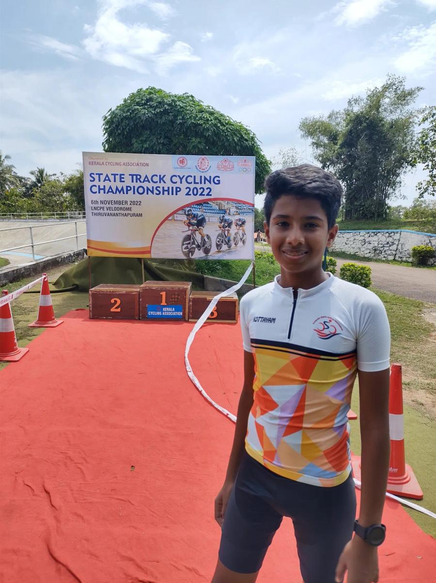 Juan in a Kottayam jersey beside the podium at the 2022 Kerala State Track Cycling Championship, LNCPE Velodrome, Thiruvananthapuram