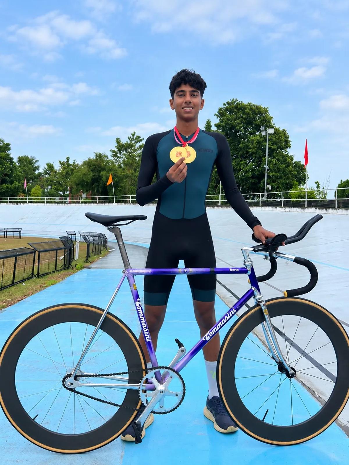 Juan Joy at the velodrome holding two gold medals beside his track bike
