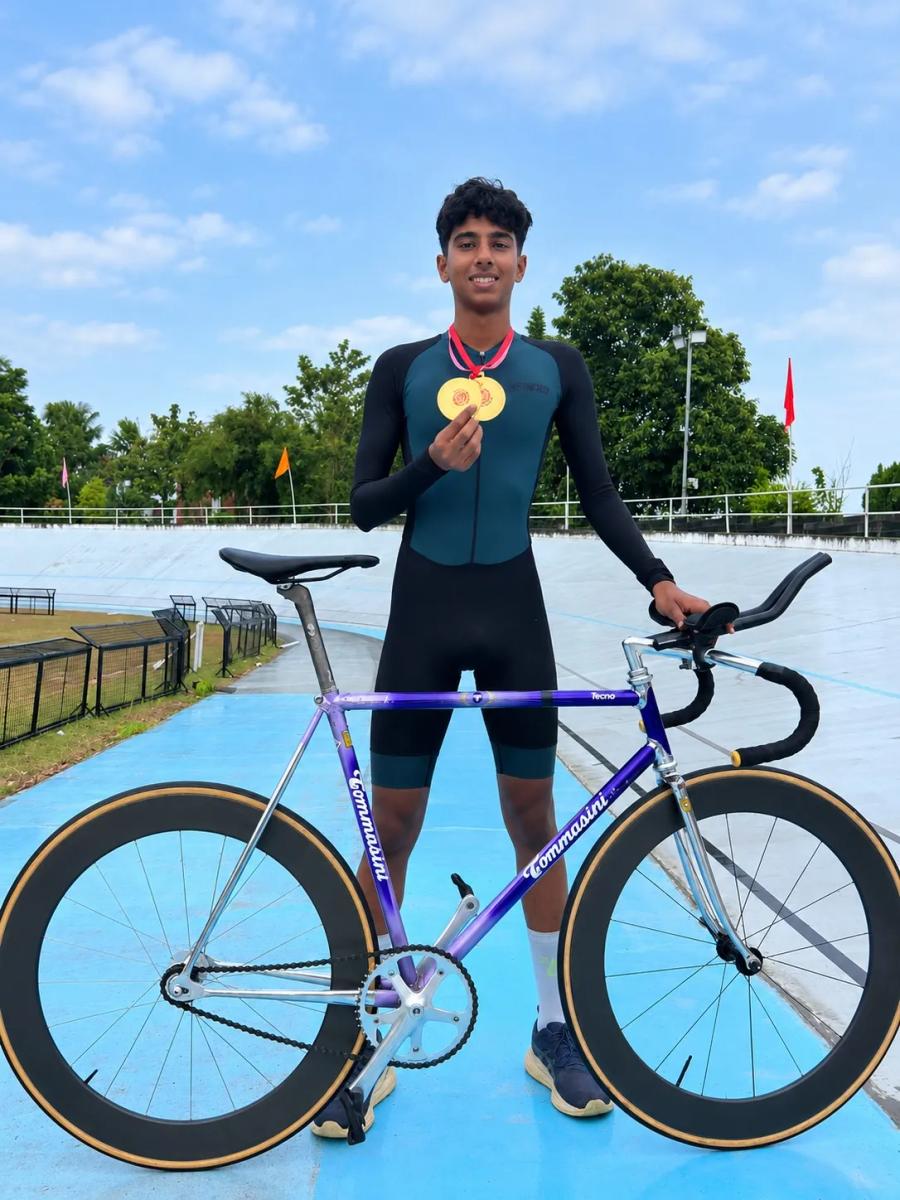 Juan Joy at the velodrome holding two gold medals beside his track bike