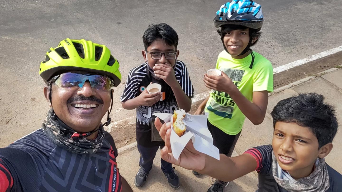 Children and an Anil enjoying tea and a vada during a cycling stop.