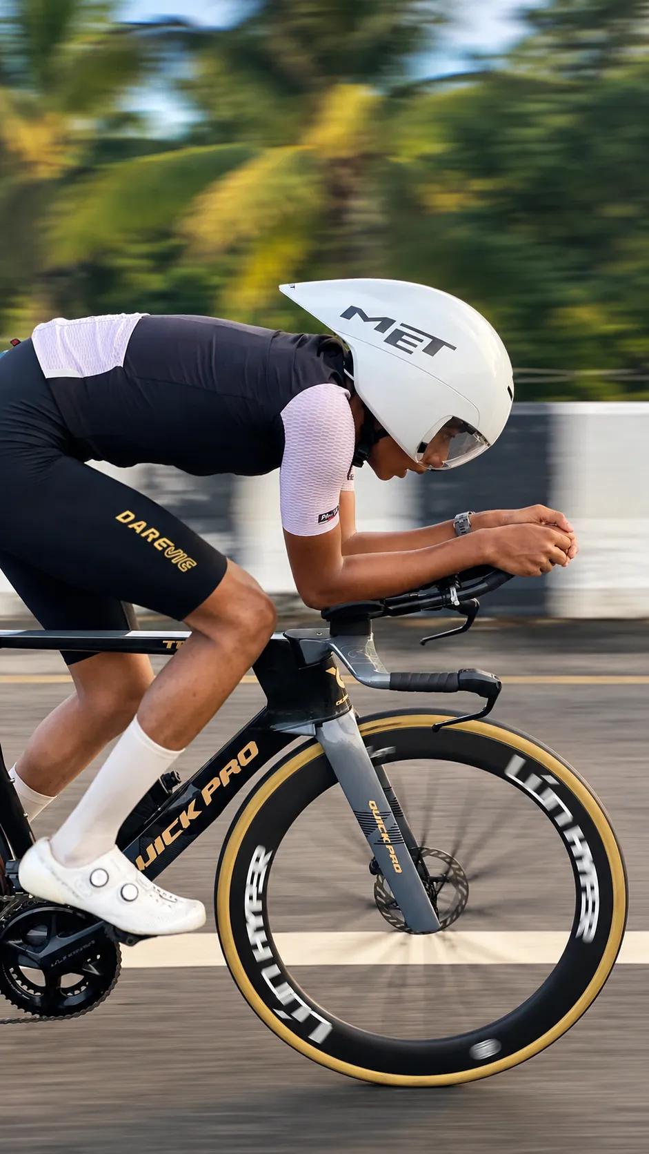 Juan in a low time-trial position, side view, with the background blurred by speed