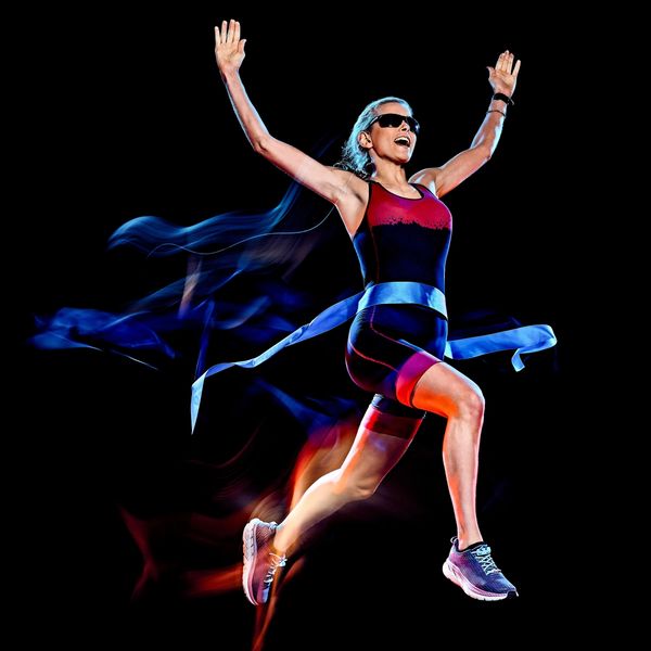 kvinne løper i mål med hendene i været