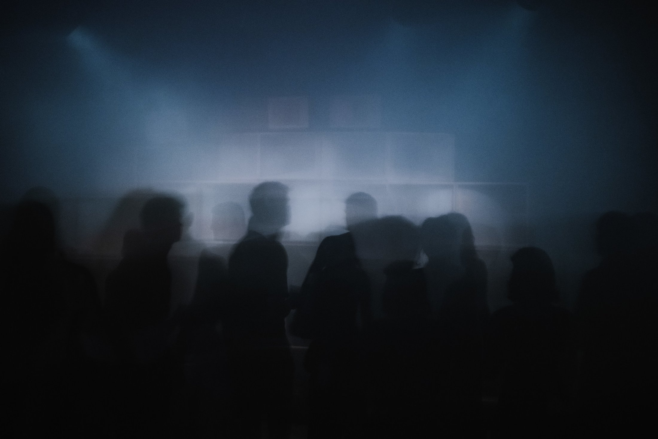 Dark electronic music night with sound system at the background and a crowd in the foreground