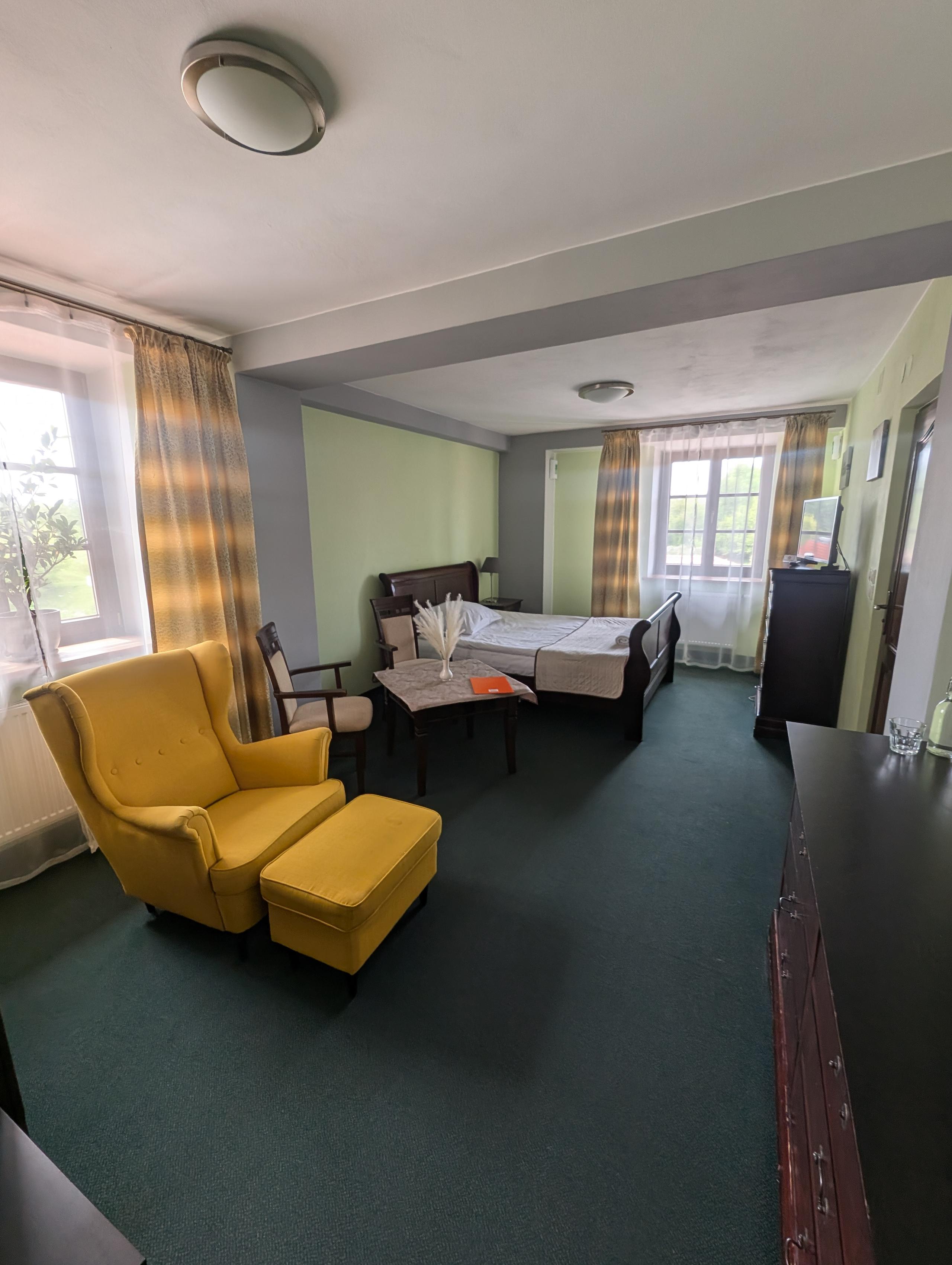 Pokój hotelowy z łóżkiem i fotelem przygotowany dla uczestników wydarzenia