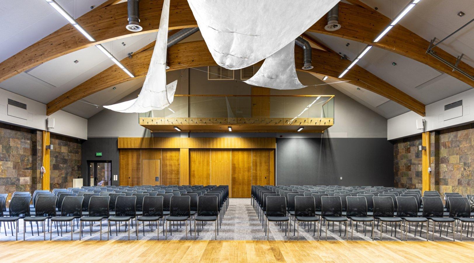 Sala konferencyjna z sceną i nowoczesnym oświetleniem.