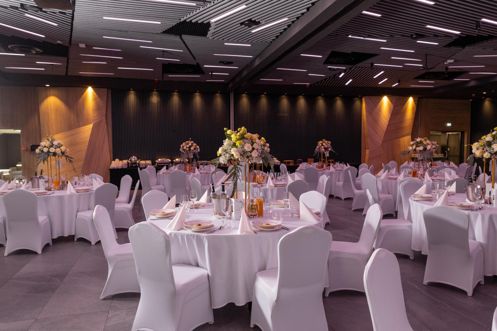 Elegancka sala bankietowa z okrągłymi stołami przygotowana na galę lub uroczystą kolację firmową.