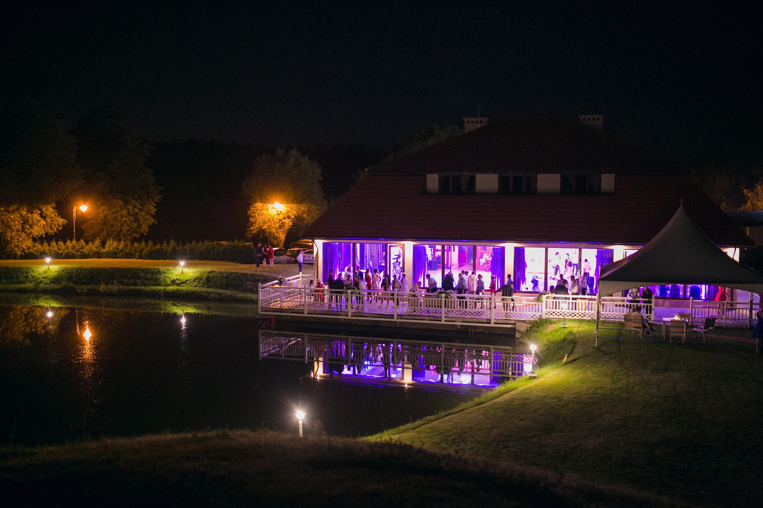 Oświetlony hotel eventowy z odbiciem w wodzie – nocna sceneria imprezy