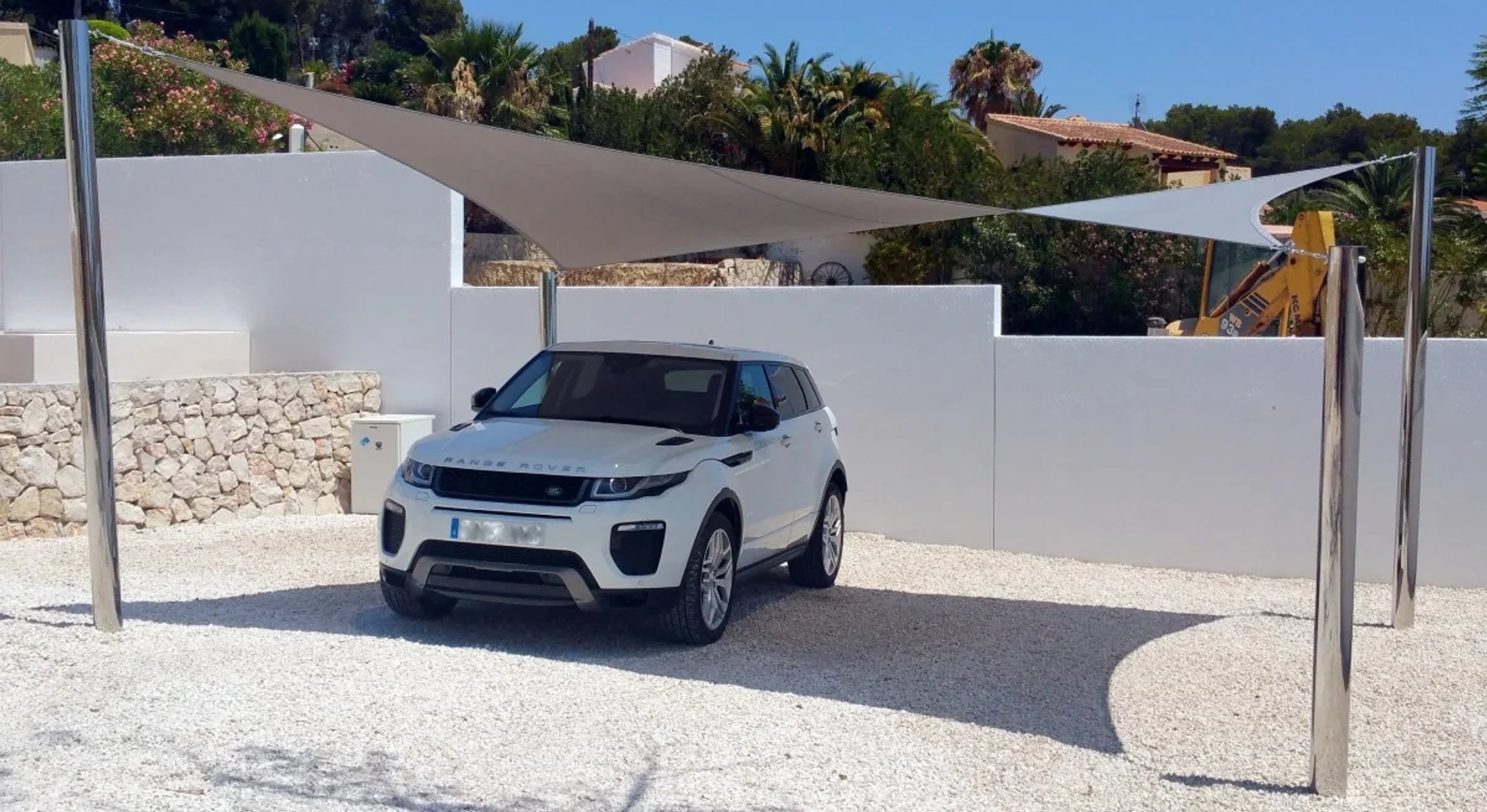Groot driehoekig schaduwdoek als carport geïnstalleerd boven een oprit in Spanje