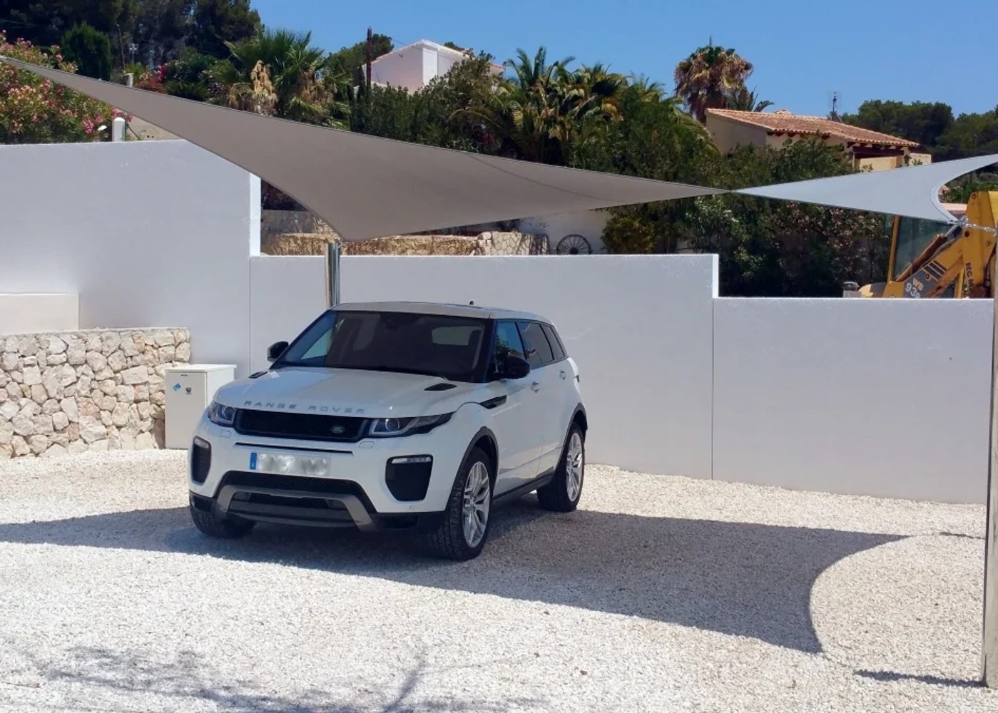 Groot driehoekig schaduwdoek als carport geïnstalleerd boven een oprit in Spanje