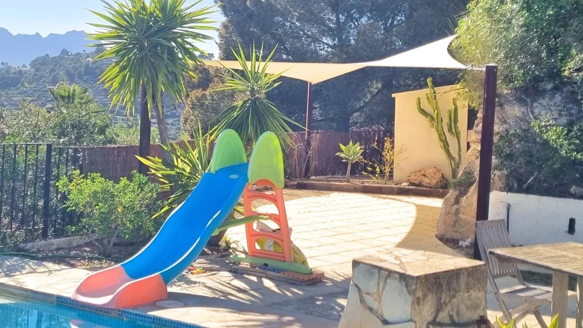 Triangular shade sail installed above a terrace play area near a swimming pool