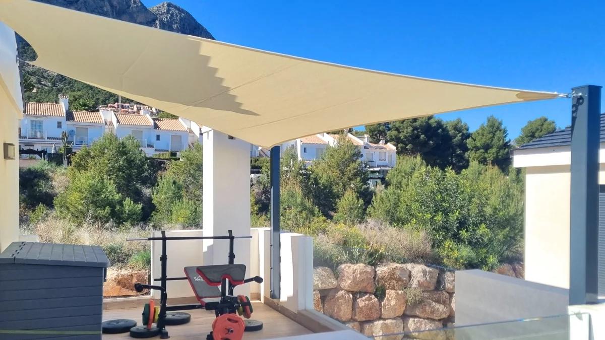Triangular shade sail installed above a modern terrace with mountain view