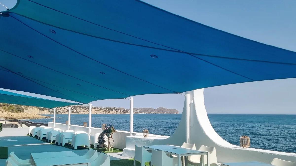 Groot blauw schaduwdoek boven een terras aan zee aan de Costa Blanca