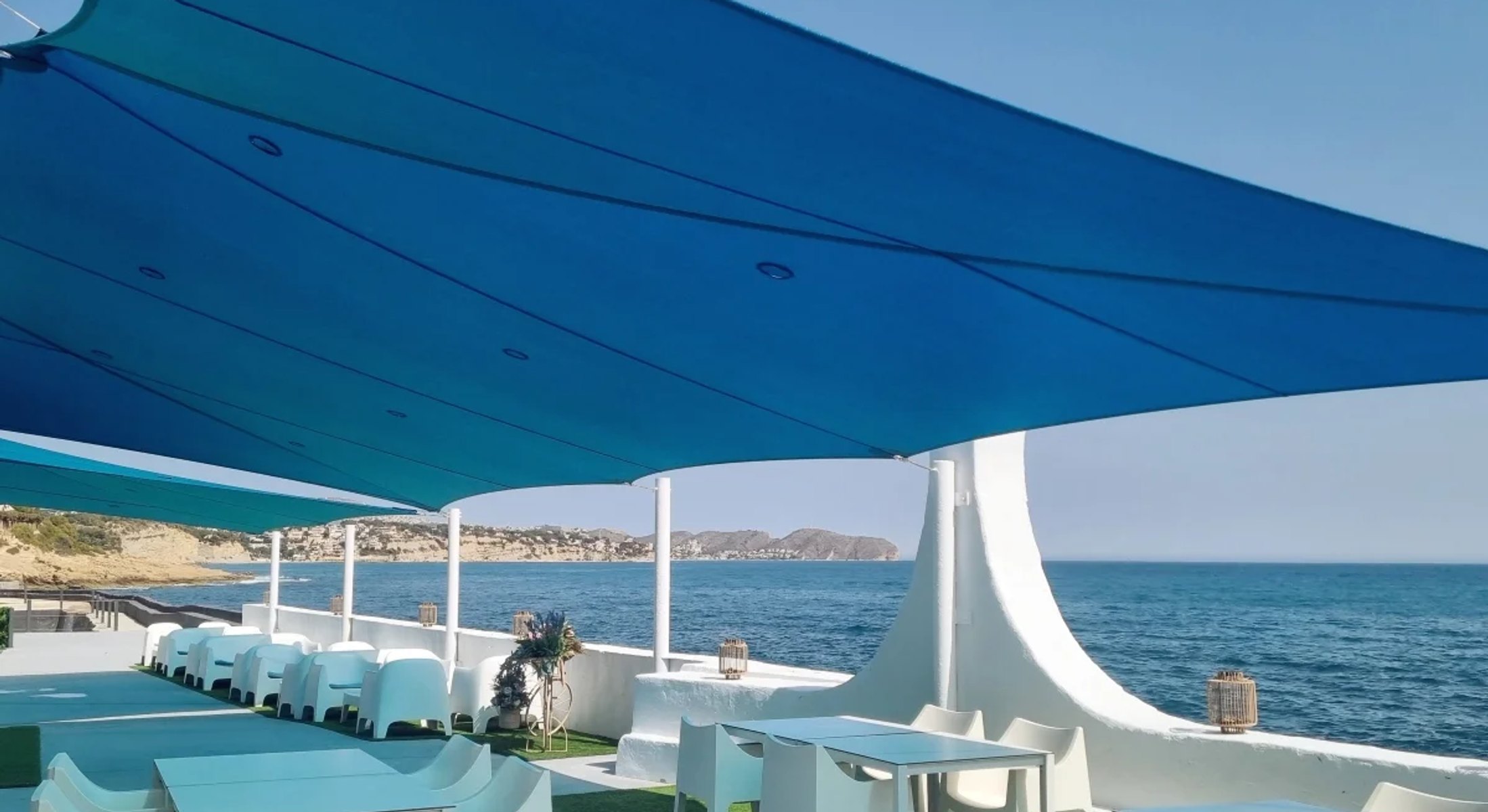 Groot blauw schaduwdoek boven een terras aan zee aan de Costa Blanca