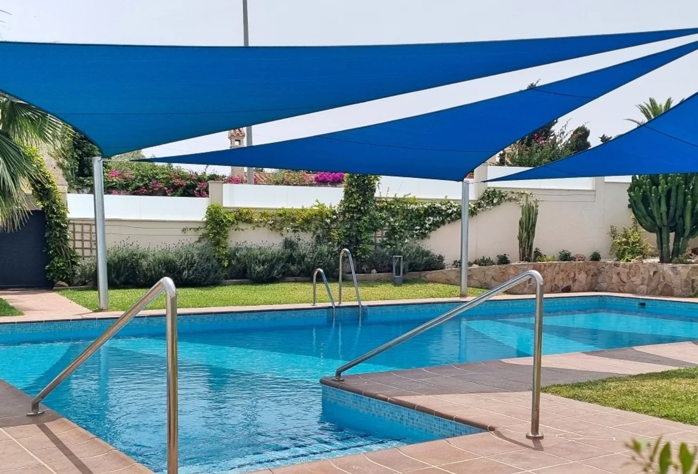 Large shade sails installed around a luxury swimming pool terrace