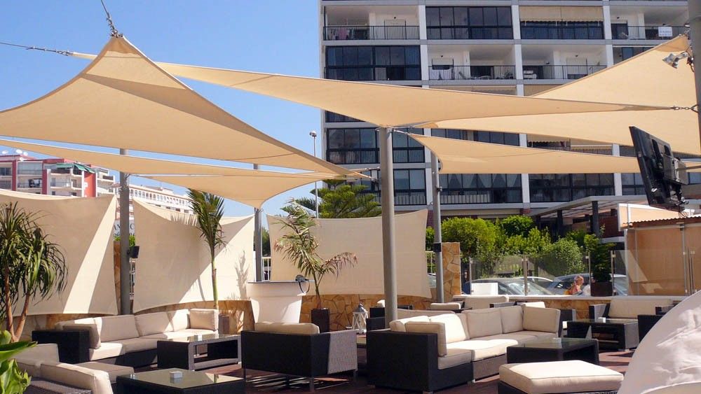 Multiple shade sails installed above a commercial lounge terrace providing sun protection for guests