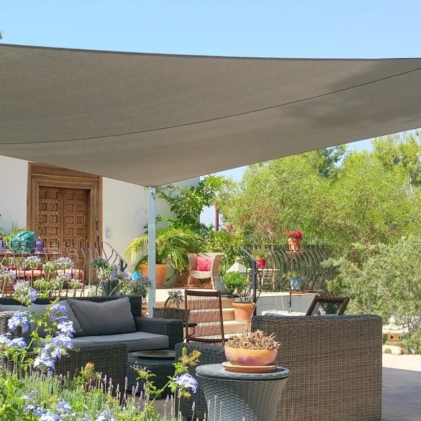 Large shade sail above an outdoor seating area in a Mediterranean garden