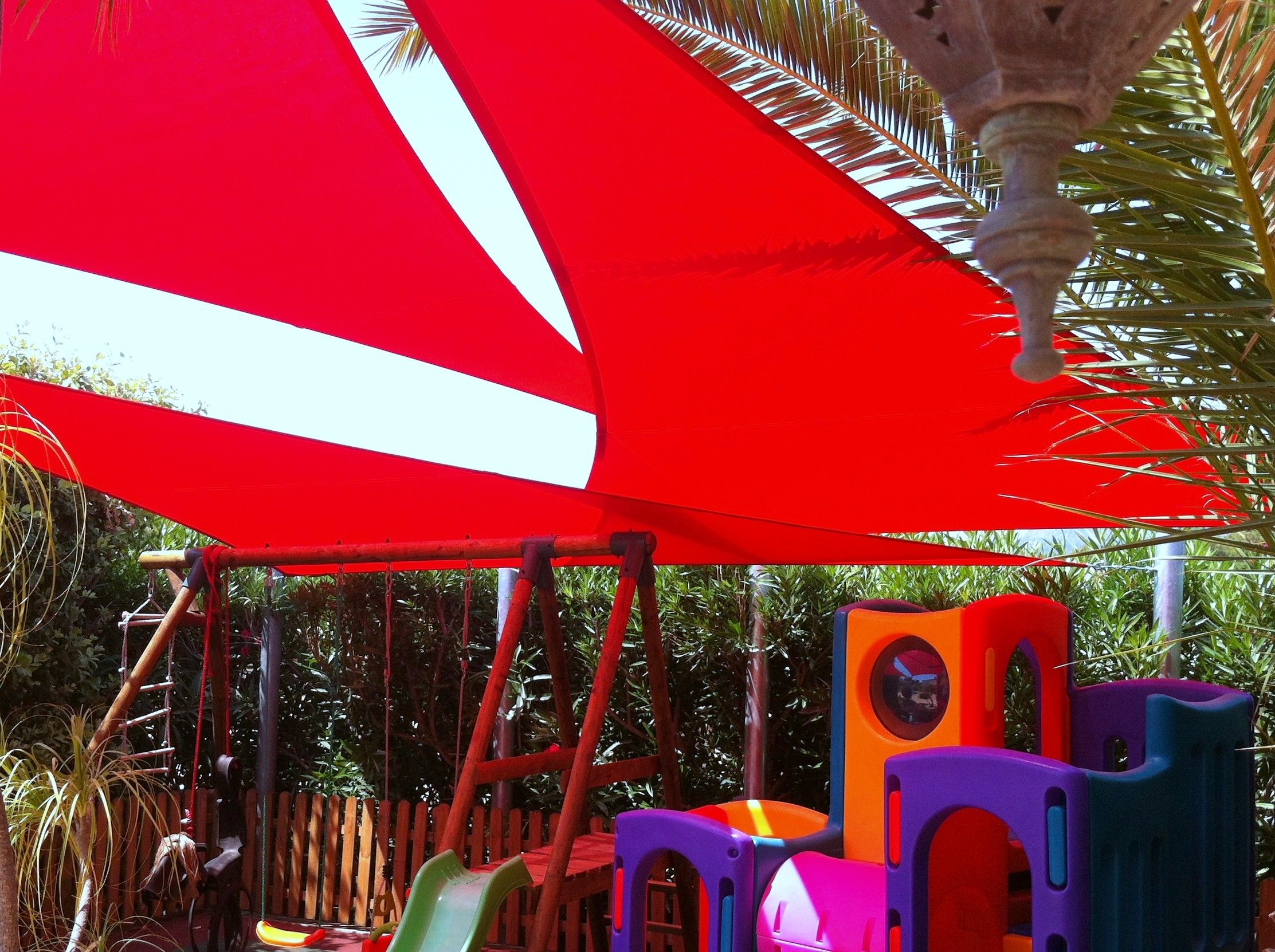 Rode schaduwdoeken geïnstalleerd boven een speelplaats voor kinderen voor schaduw en UV-bescherming