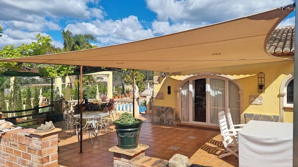 Large rectangular shade sail installed above a traditional Mediterranean terrace