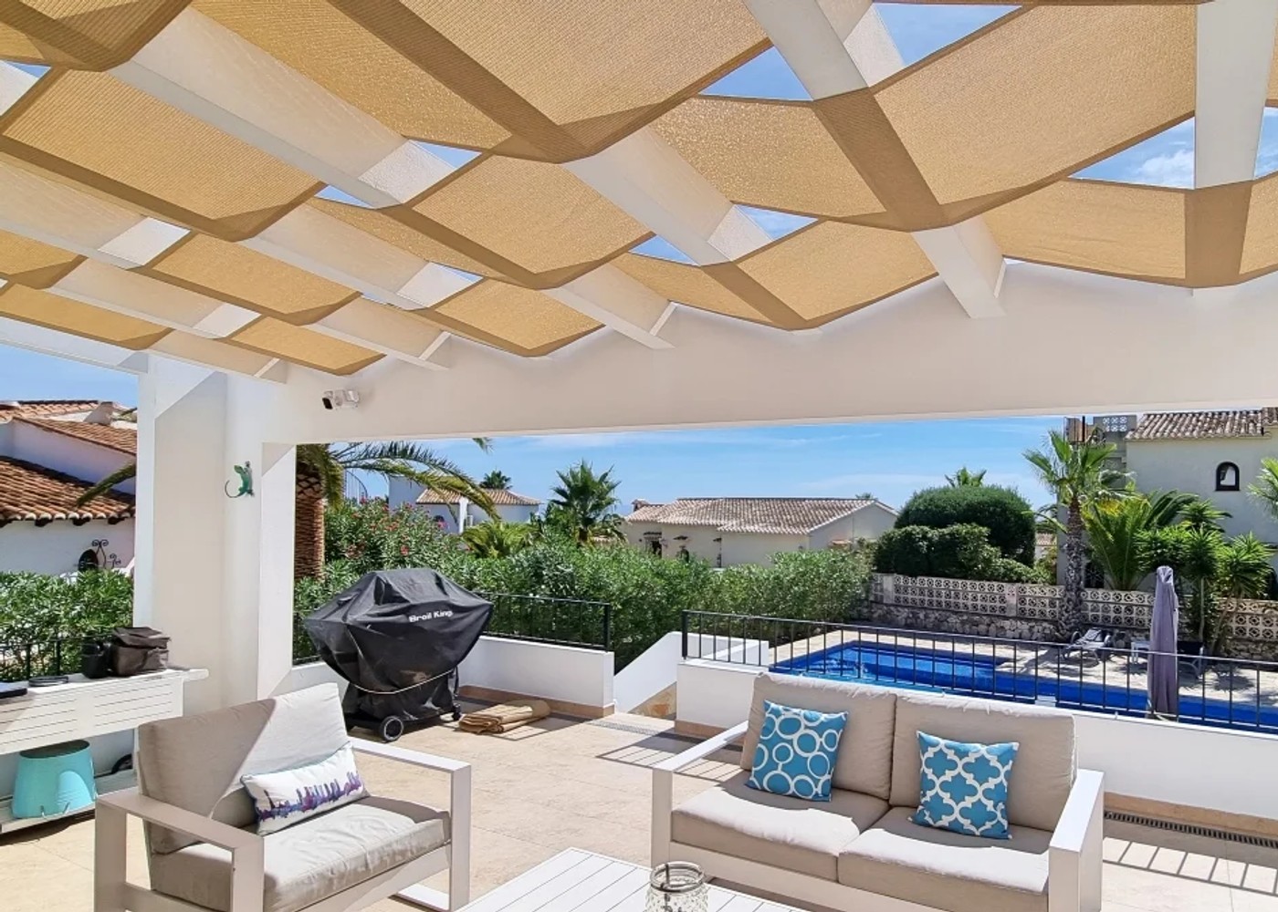 Pergoladak met geweven schaduwpanelen boven een zithoek op het terras