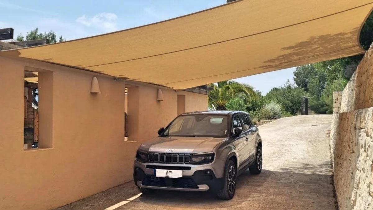 Rechthoekig schaduwdoek geïnstalleerd boven een oprit voor schaduw bij een geparkeerde auto