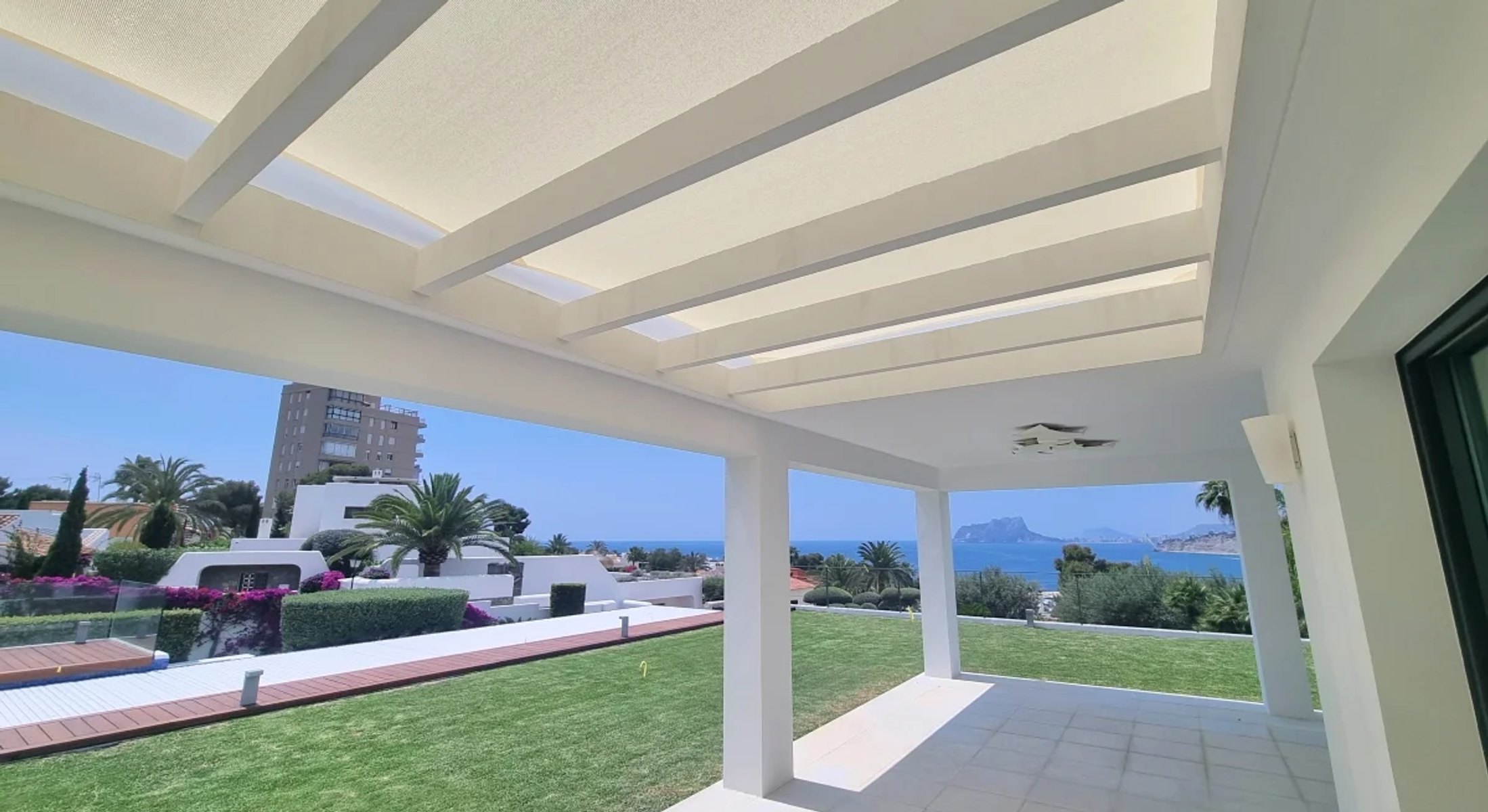 Modern white pergola structure with integrated shade sail system