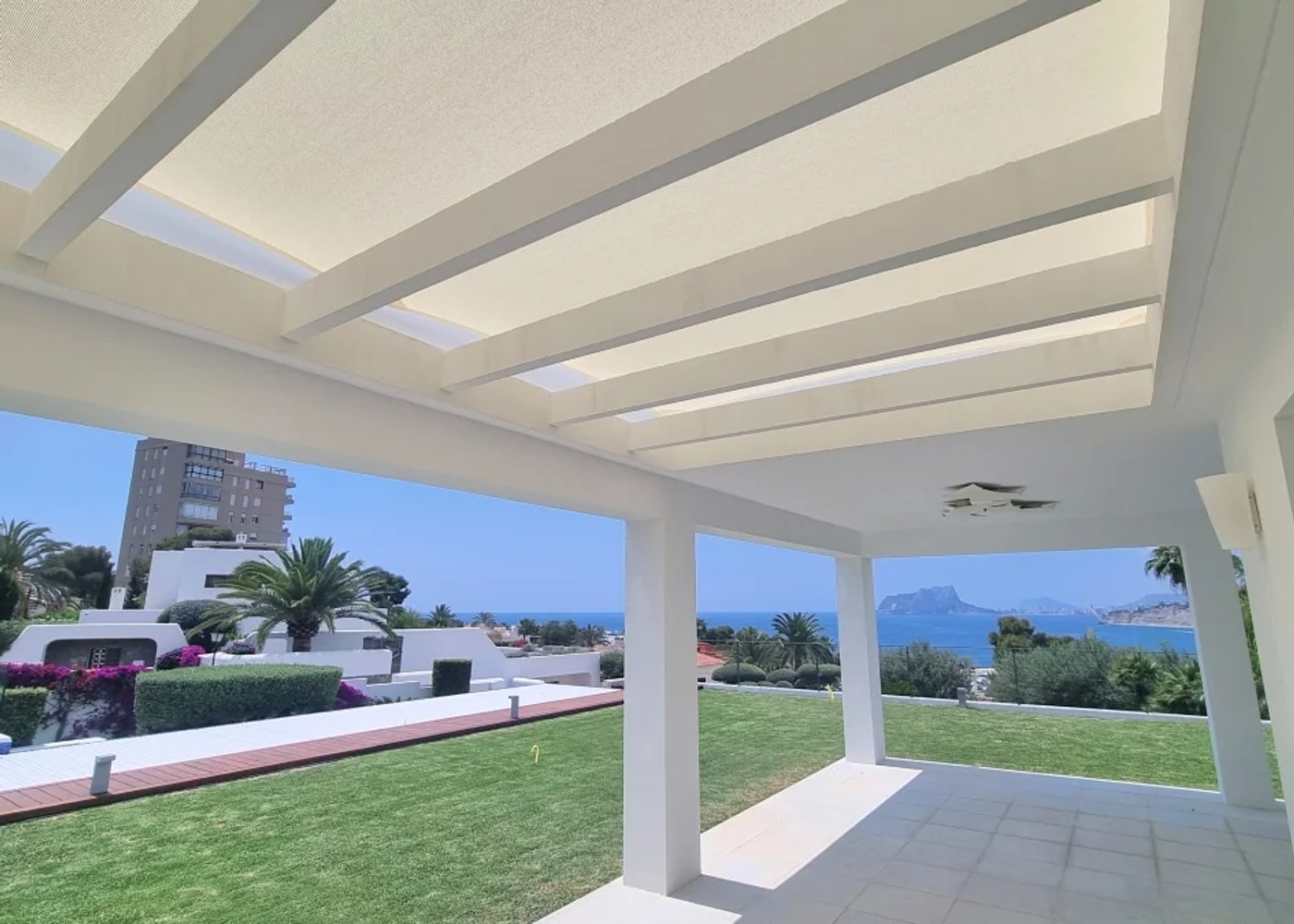 Modern white pergola structure with integrated shade sail system