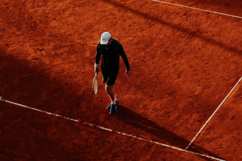 An overhead view of a tennis player holding a racket on a clay court.