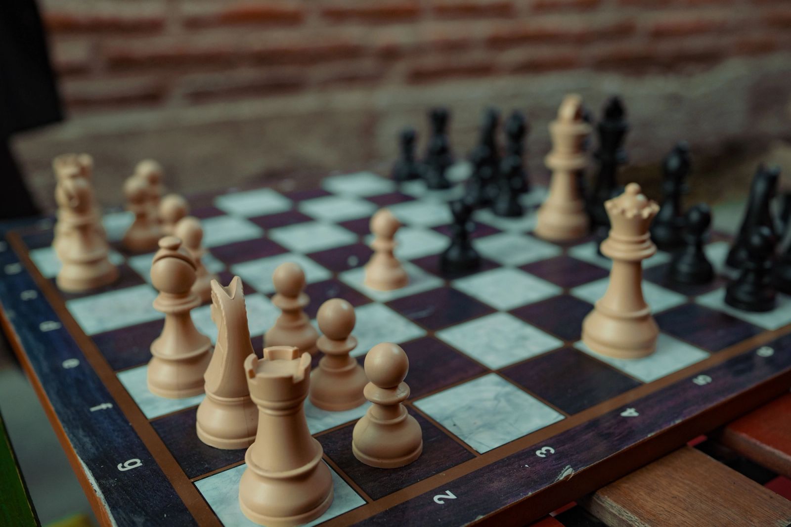 A wooden chessboard with white and black pieces in play.