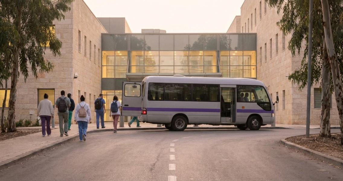 מיניבוס הסעות משמרות מוריד צוות רפואי בכניסת העובדים של בית חולים לפנות בוקר.