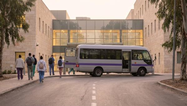מיניבוס הסעות משמרות מוריד צוות רפואי בכניסת העובדים של בית חולים לפנות בוקר.
