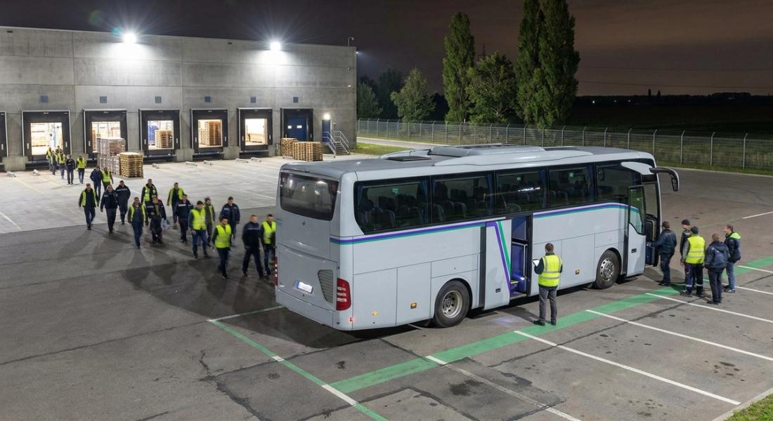 Нічна пересменка біля розподільчого центру за містом: працівники сідають у службовий автобус під освітленими доками