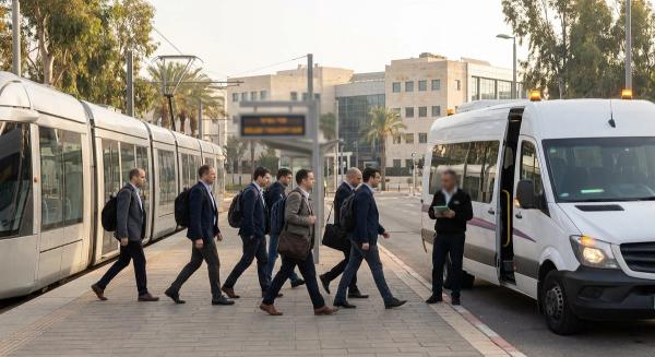 רכבת קלה של הקו האדום בתחנת קריית אריה בפתח תקווה ברקע מגדלי משרדים, לצד אוטובוס שאטל ארגוני יוצא מתחנת הרכבת לכיוון פארק הרצליה פיתוח