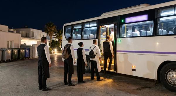 Personal de hotel con uniforme sube a una lanzadera de empresa en la entrada de servicio de un resort balear de madrugada.