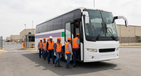 Autobús de transporte de personal en la entrada de un parque industrial mexicano, con trabajadores abordando de día