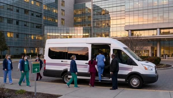 Hospital staff shuttle picking up nurses outside a multi-campus medical center at shift change