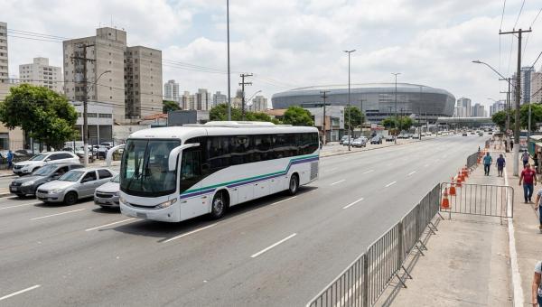 Autobús de transporte de personal en una avenida en día de partido, junto a vallas y perímetro cerrado cerca de un estadio.