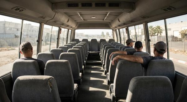 פנים מיניבוס הסעות עובדים באמצע היום, ארבעה נוסעים בלבד פזורים בין מושבים ריקים באור שמש נמוך