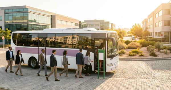 Empleados subiendo a un autobús lanzadera corporativo en un polígono empresarial español por la mañana