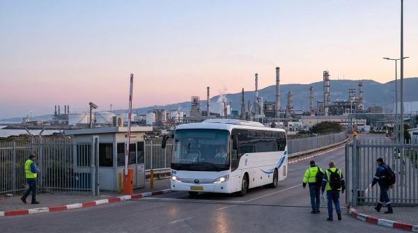 שאטל עובדים מגיע לשער מפעל תעשייה בחילופי משמרת בבוקר מוקדם