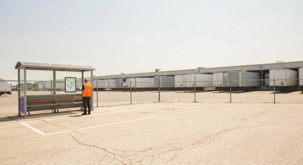 Empty marked shuttle bay at a distribution center in summer, a planner with a tablet beside it, loaded trailers behind