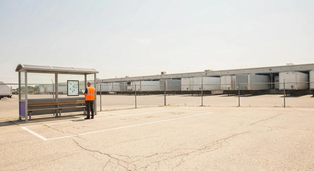 Empty marked shuttle bay at a distribution center in summer, a planner with a tablet beside it, loaded trailers behind