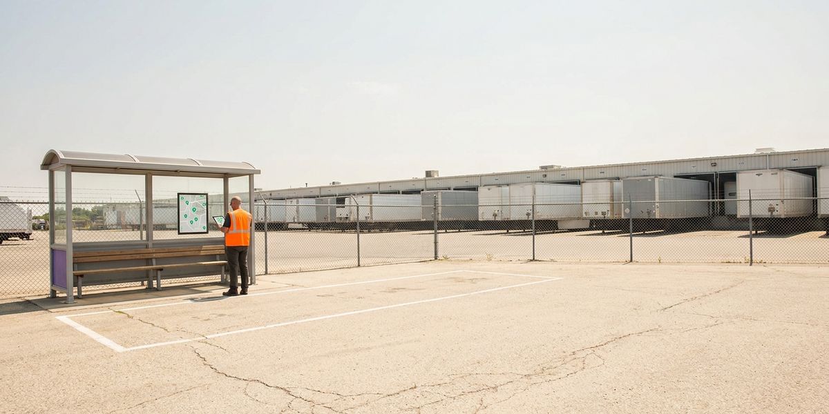 Empty marked shuttle bay at a distribution center in summer, a planner with a tablet beside it, loaded trailers behind