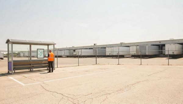 Empty marked shuttle bay at a distribution center in summer, a planner with a tablet beside it, loaded trailers behind