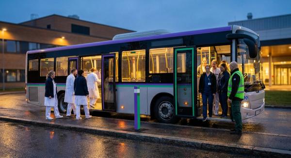 Службовий автобус біля входу в лікарню в сутінках: одна зміна медпрацівників виходить, інша заходить у салон.