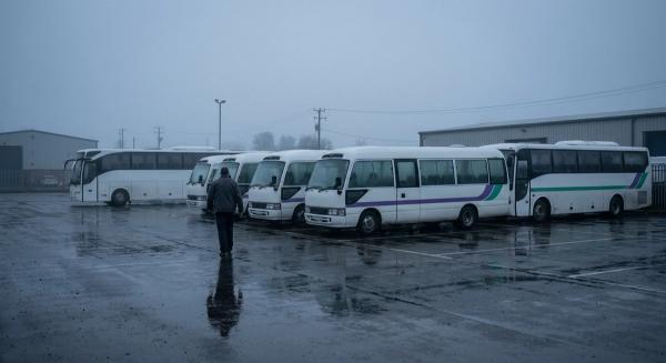 Напівпорожнє депо службового розвезення на світанку: припарковані мікроавтобуси з порожніми кабінами й самотній водій