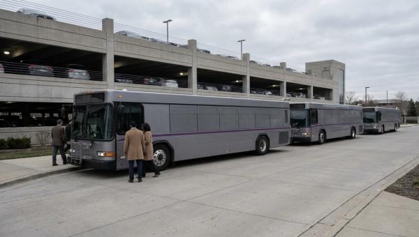 Employee shuttle bus loading at a suburban corporate campus next to a half-empty parking structure