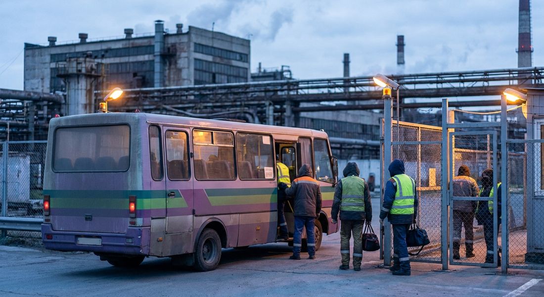 Заводський мікроавтобус забирає нічну зміну біля прохідної підприємства у промзоні вдосвіта