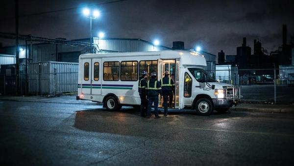 Заводський автобус забирає працівників нічної зміни біля прохідної промзони пізно ввечері