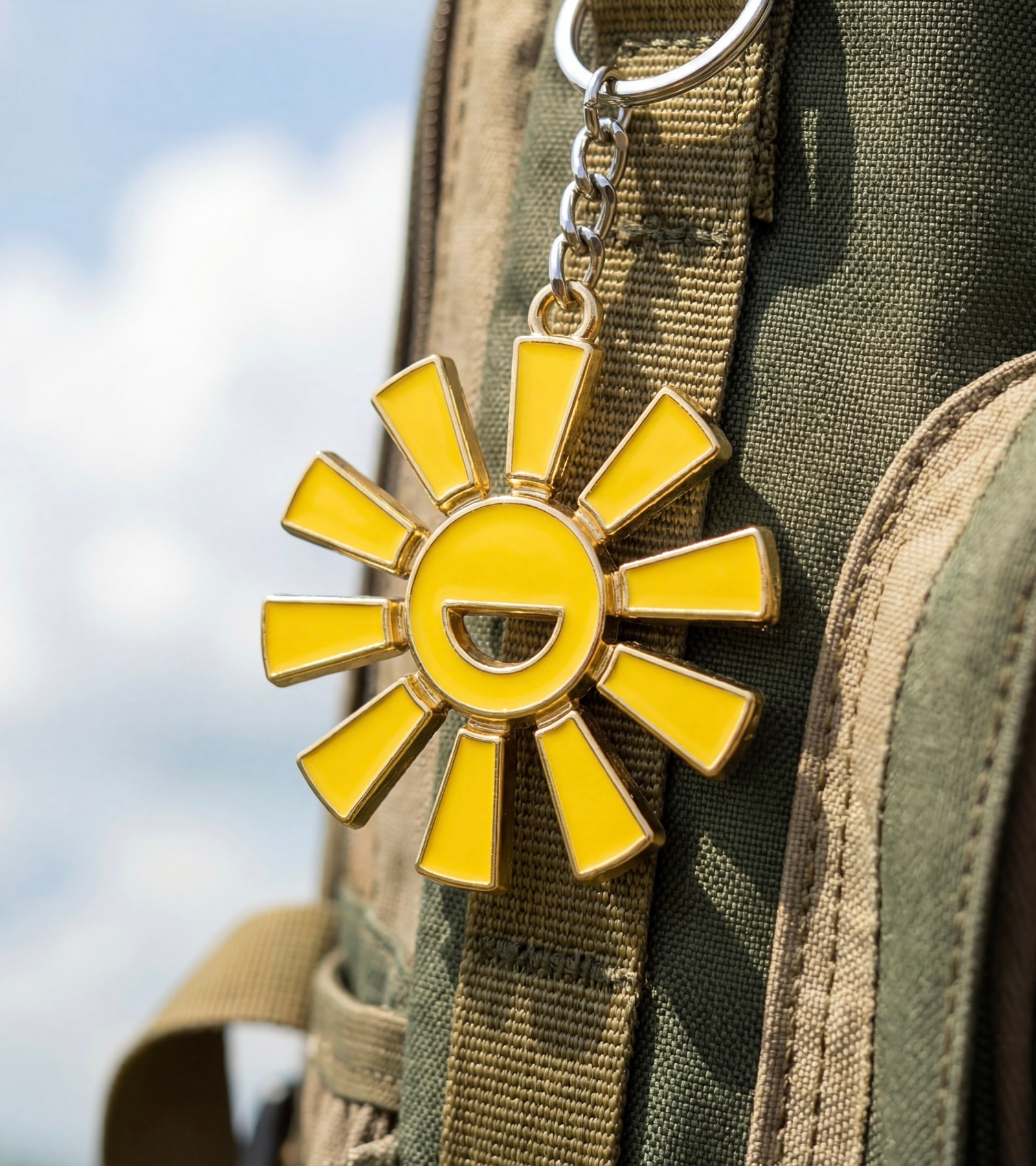 Yellow Campsi sun icon keychain attached to a backpack